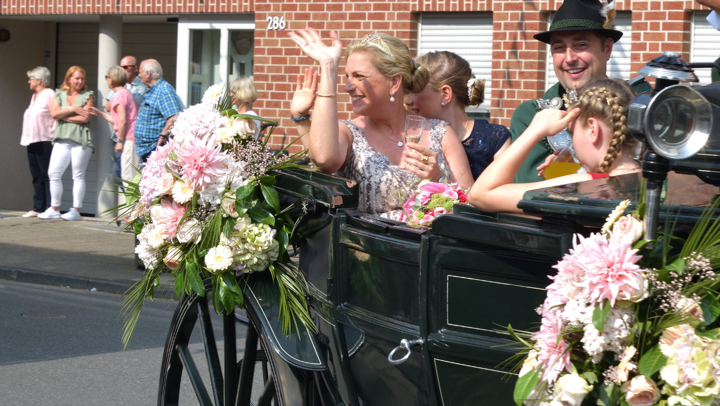 Unser Königspaar Thomas III. und Sabine Schier ge­nießt ein weiteres Mal die Kutsch­fahrt durch Flehe, dies­mal in Begleitung der scheiden­den Pagen­königin Melinda Henning­haus und der zu krönen­den Pagen­königin Paulina Schier.